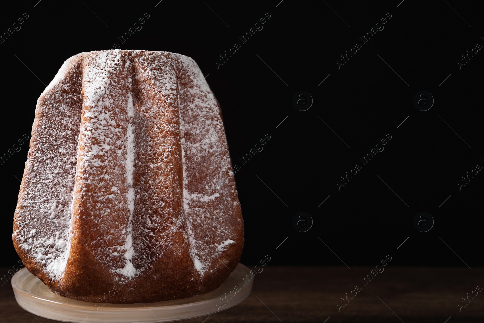 Photo of Delicious Pandoro cake decorated with powdered sugar on wooden table, space for text. Traditional Italian pastry
