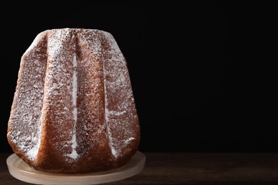 Photo of Delicious Pandoro cake decorated with powdered sugar on wooden table, space for text. Traditional Italian pastry