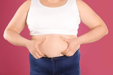 Overweight woman on color background, closeup. Obesity and weight loss