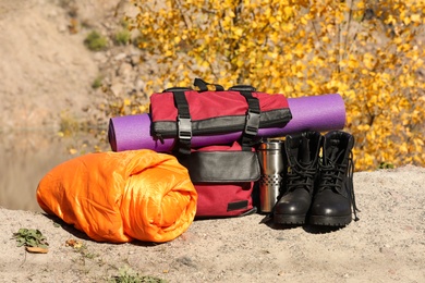 Set of camping equipment with sleeping bag on ground outdoors