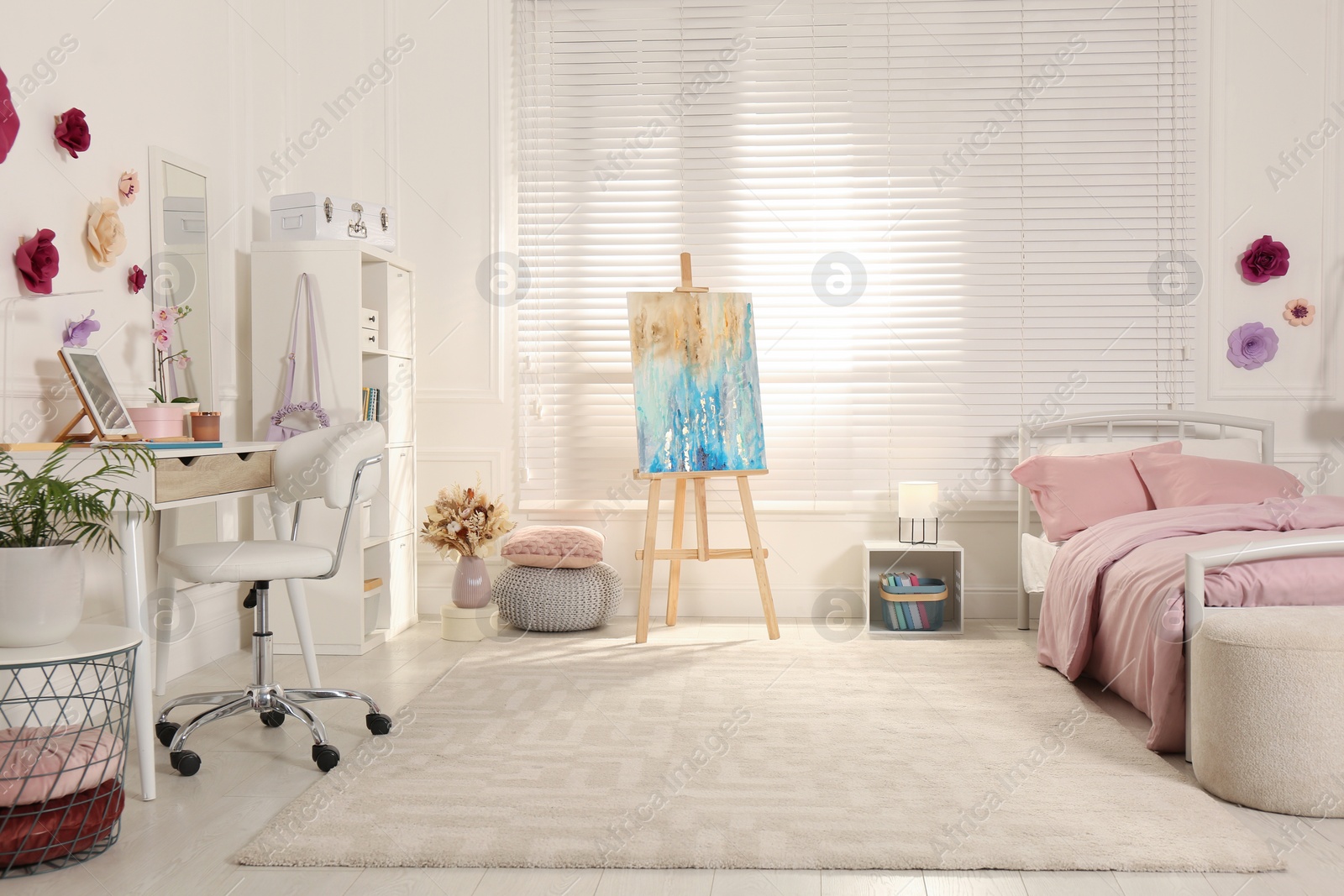 Photo of Stylish teenager's room interior with computer, comfortable bed and painting easel