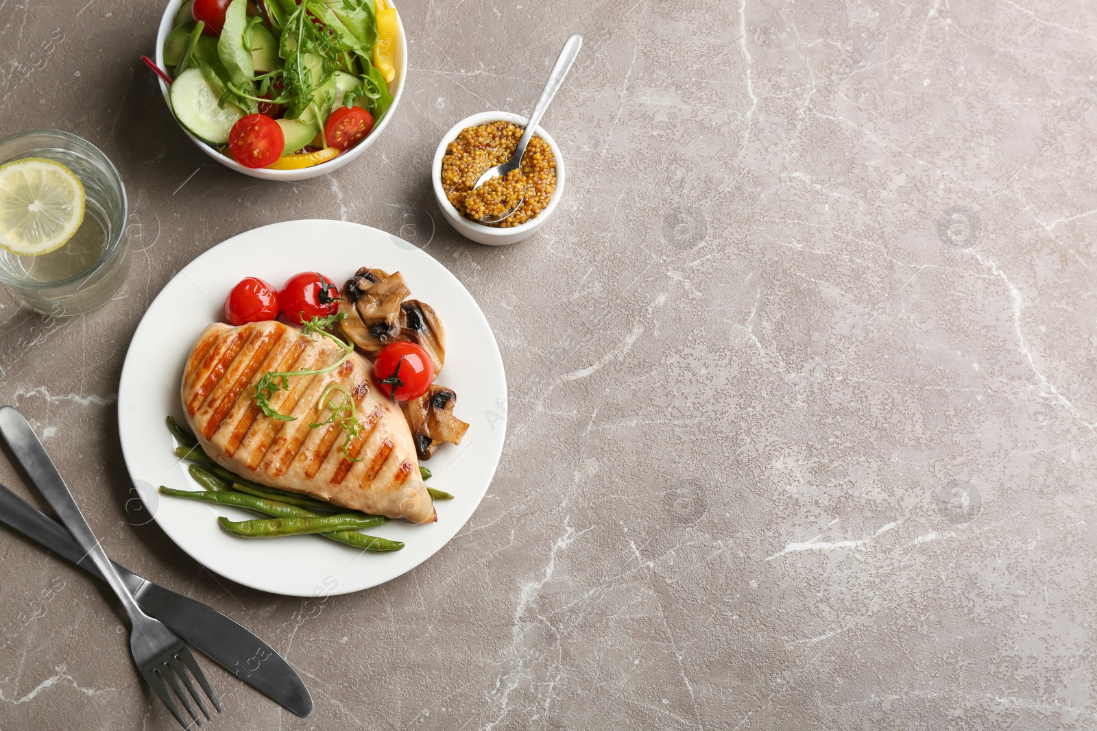 Photo of Tasty grilled chicken fillet served on brown marble table, flat lay. Space for text