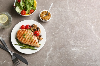 Tasty grilled chicken fillet served on brown marble table, flat lay. Space for text