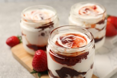 Photo of Tasty yoghurt with jam and strawberries on grey table, closeup