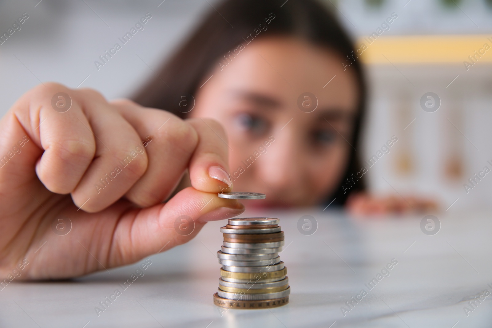 Photo of Young woman stacking coins at table, focus on hand. Money savings