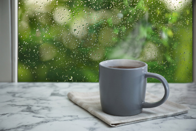 Image of Cup of hot drink near window on rainy day