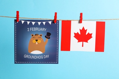 Photo of Happy Groundhog Day greeting card and Canada flag hanging on light blue background