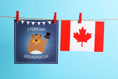 Happy Groundhog Day greeting card and Canada flag hanging on light blue background