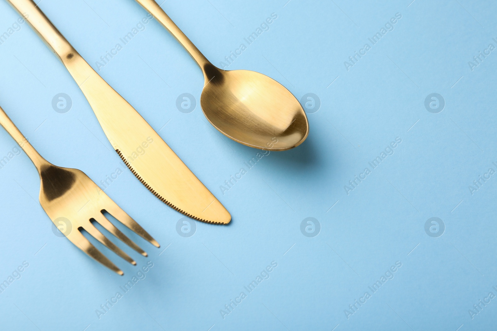 Photo of Stylish cutlery set on light blue table, above view. Space for text