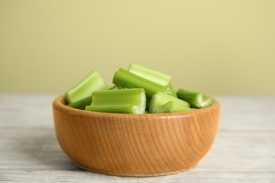 Photo of Cut celery in bowl on white wooden table. Space for text