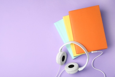 Photo of Modern headphones with hardcover books on color background, top view. Space for text