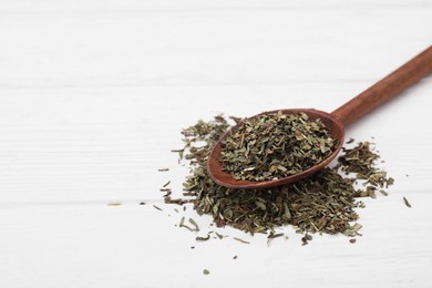 Photo of Spoon of dry tarragon on white wooden table. Space for text