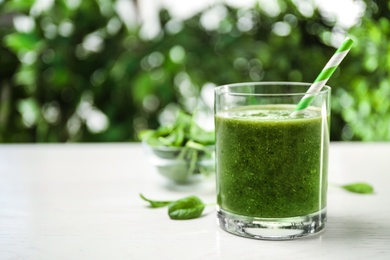 Photo of Delicious fresh green juice on white table, space for text