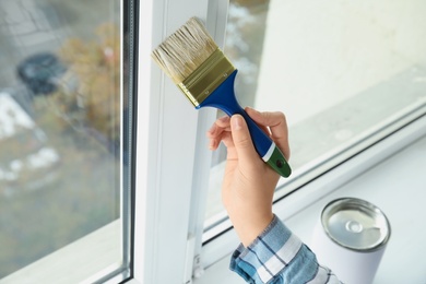 Photo of Woman painting window frame at home, closeup