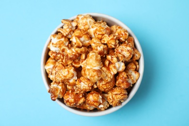 Photo of Bowl with caramel popcorn on color background, top view