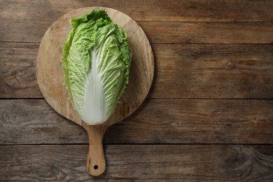 Photo of Cutting board with fresh ripe Chinese cabbage on wooden table, top view. Space for text