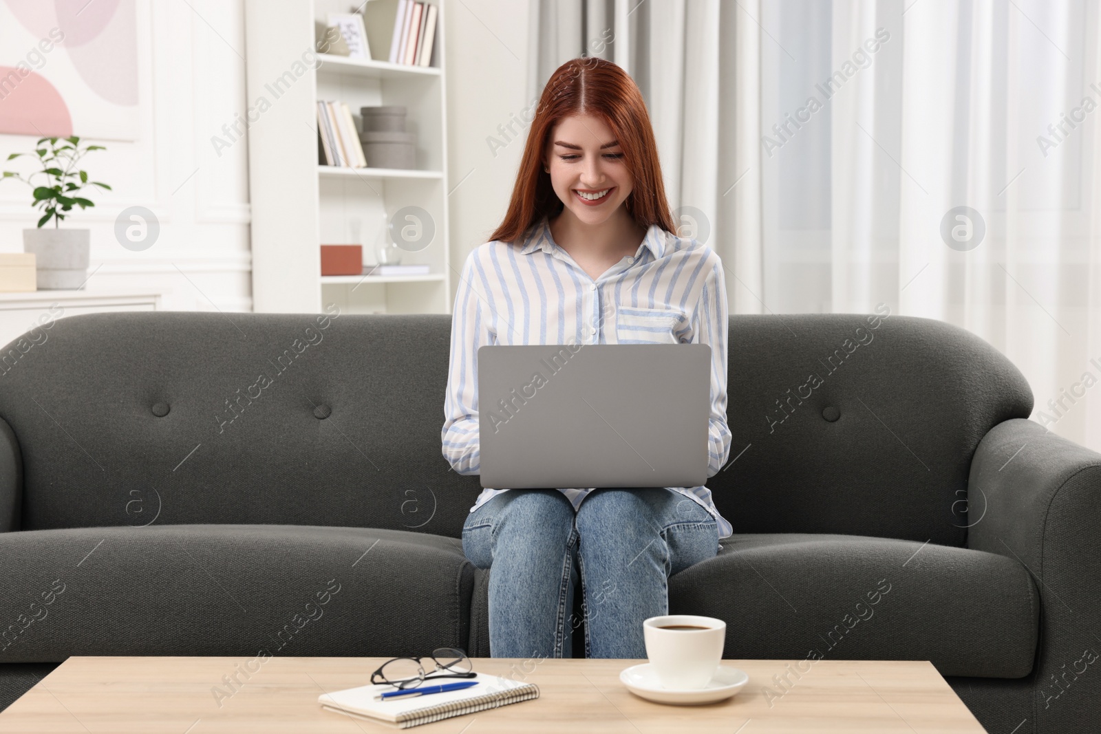 Photo of Happy woman using laptop on couch in room