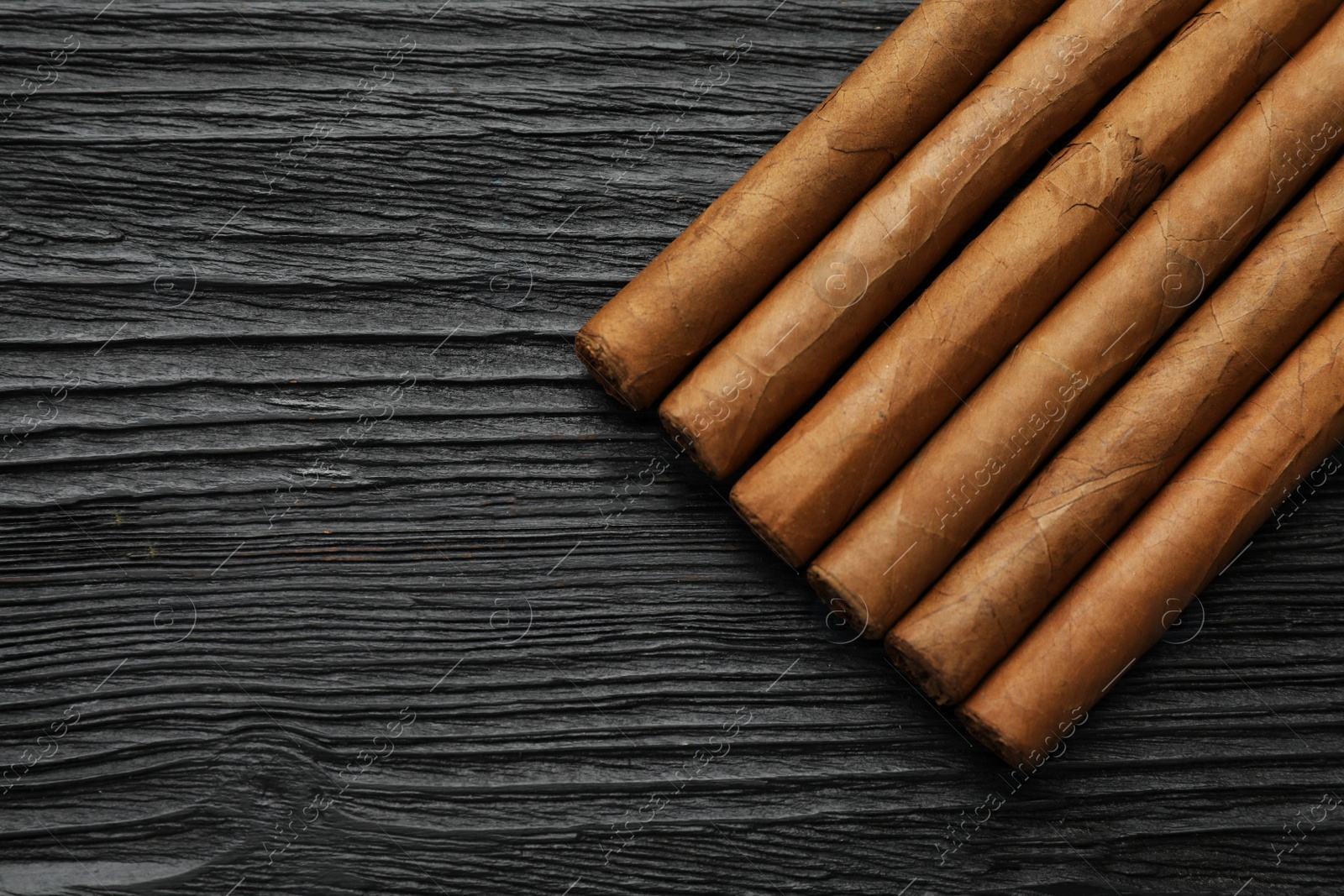 Photo of Many cigars on black wooden table, flat lay. Space for text