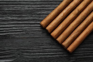 Photo of Many cigars on black wooden table, flat lay. Space for text
