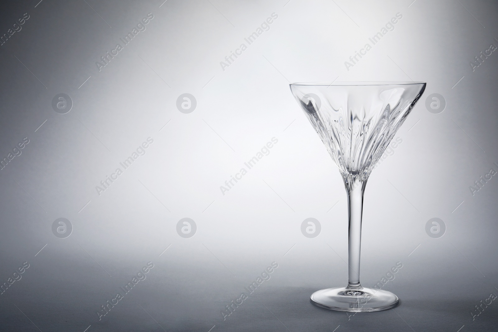 Photo of Elegant empty martini glass on grey background. Space for text