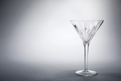 Photo of Elegant empty martini glass on grey background. Space for text