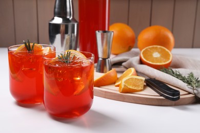 Photo of Aperol spritz cocktail, rosemary and orange slices on white wooden table