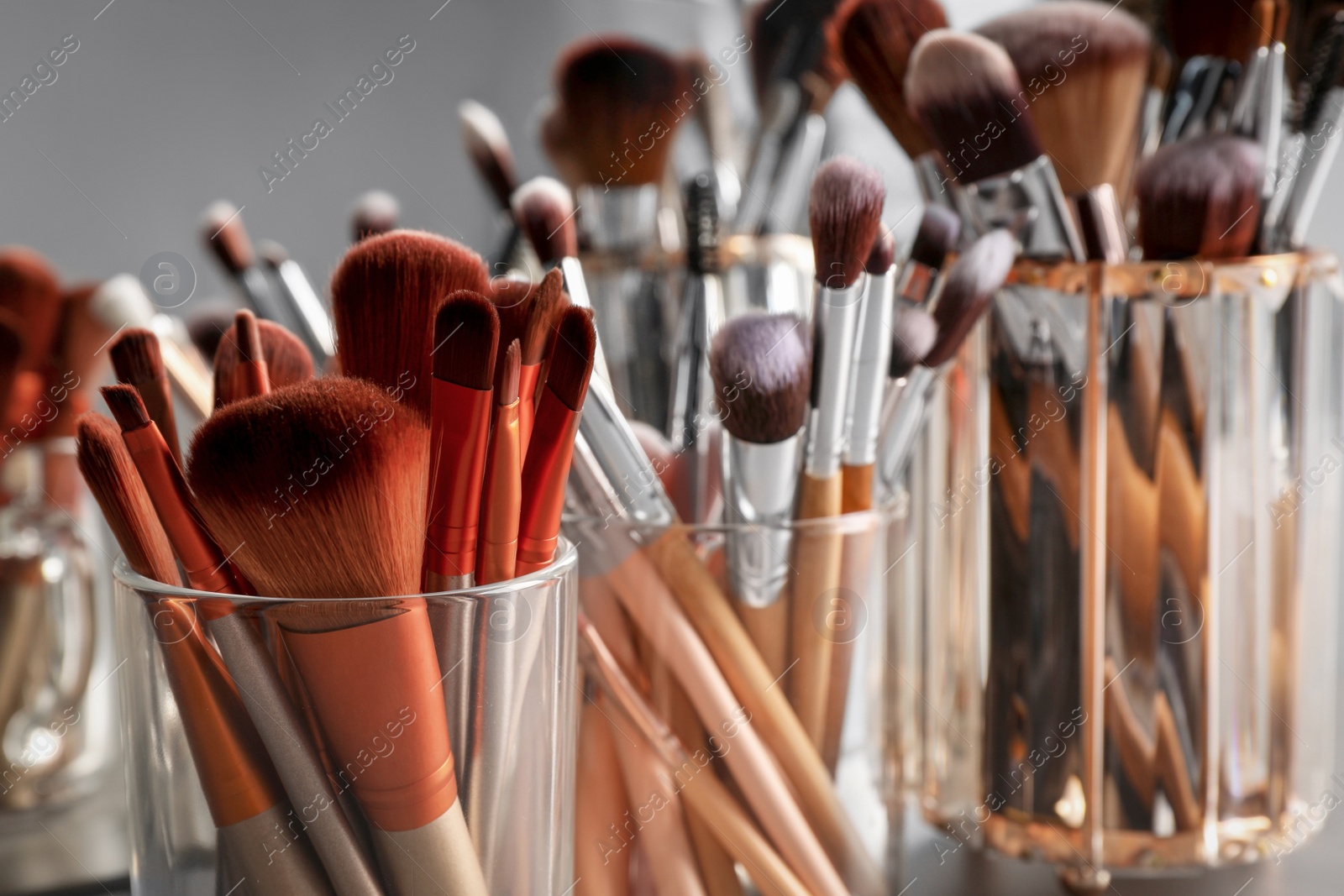 Photo of Set of professional makeup brushes near mirror, closeup