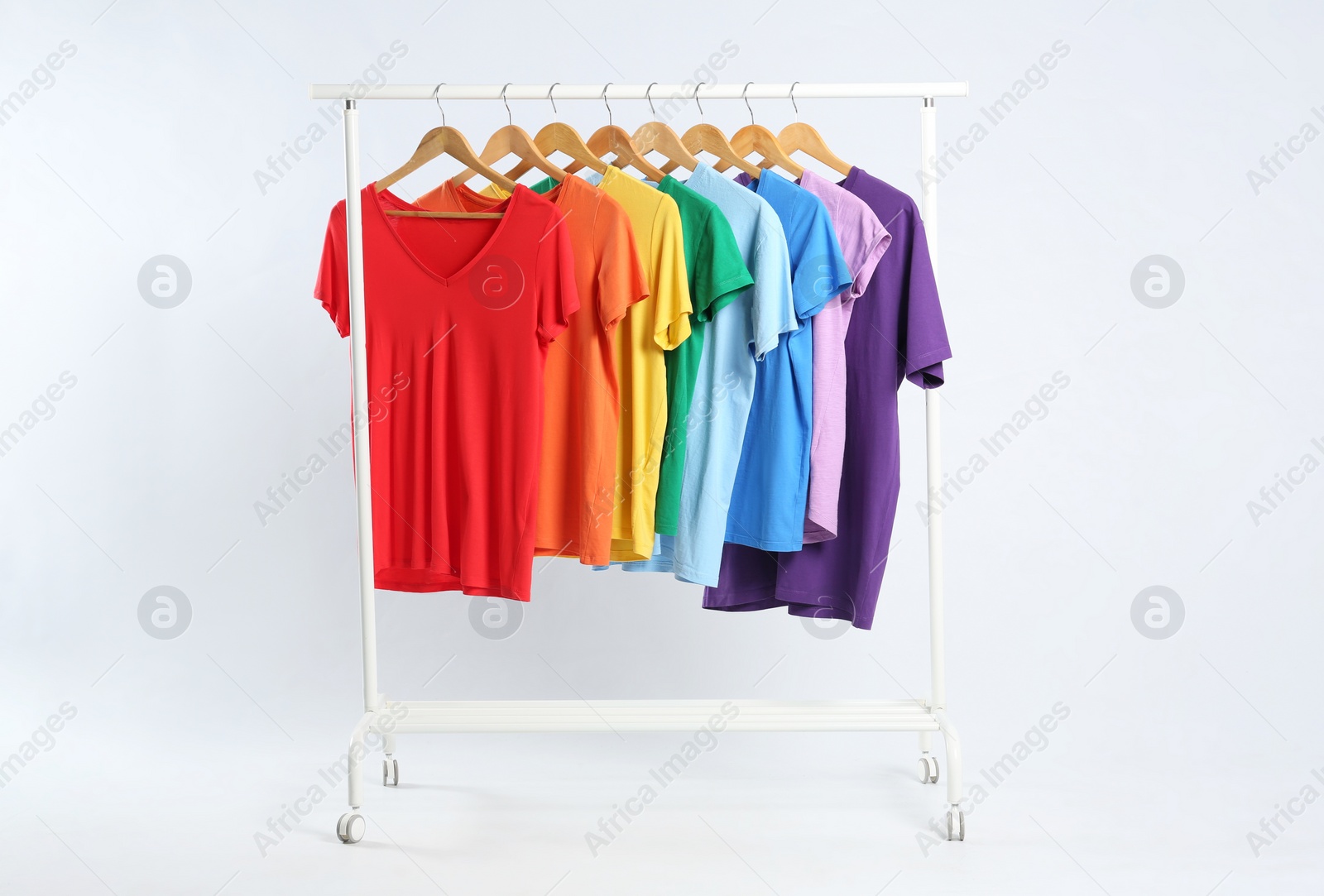 Photo of Colorful clothes hanging on rack against white background