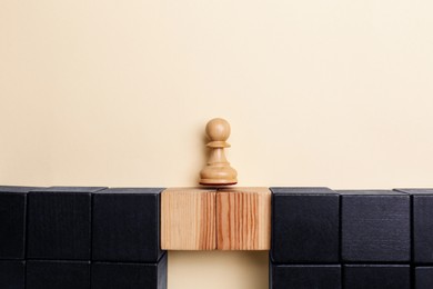 Photo of Chess piece on wooden bridge made with cubes on beige background, flat lay