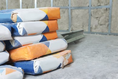 Photo of Cement powder in bags on stone floor indoors. Space for text
