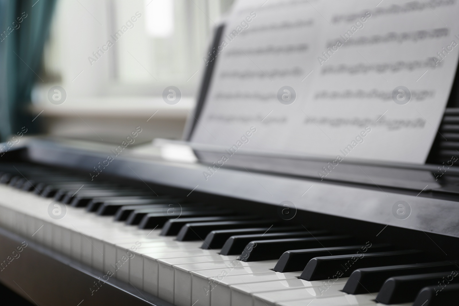 Photo of Modern piano with music sheets in room, closeup