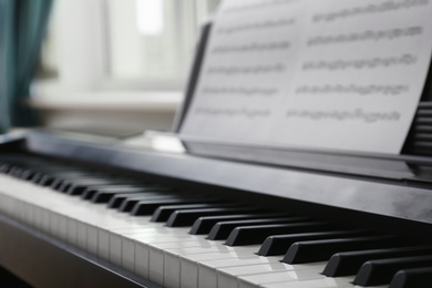 Modern piano with music sheets in room, closeup