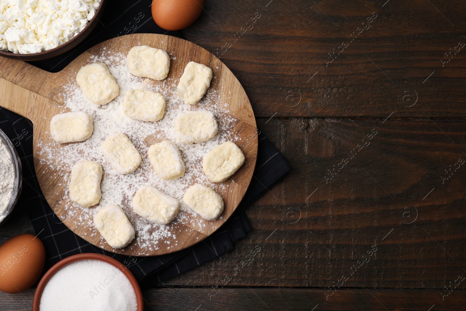 Photo of Making lazy dumplings. Board with cut dough and ingredients on wooden table, flat lay. Space for text