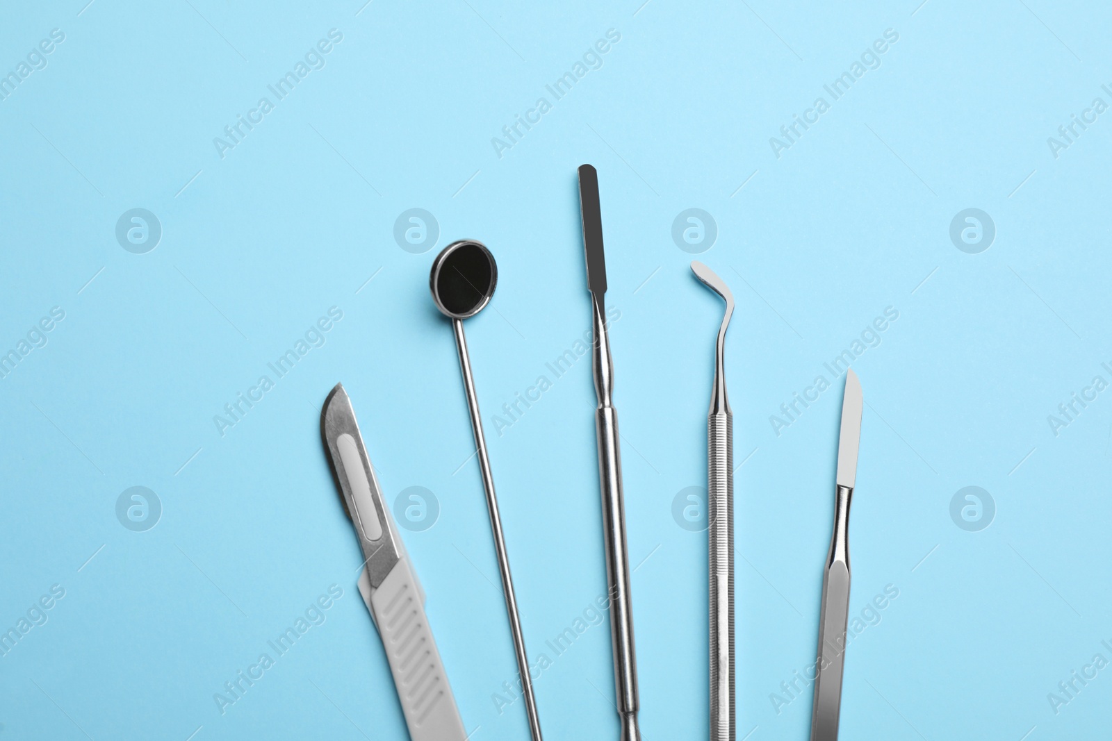 Photo of Set of different dentist's tools on light blue background, flat lay