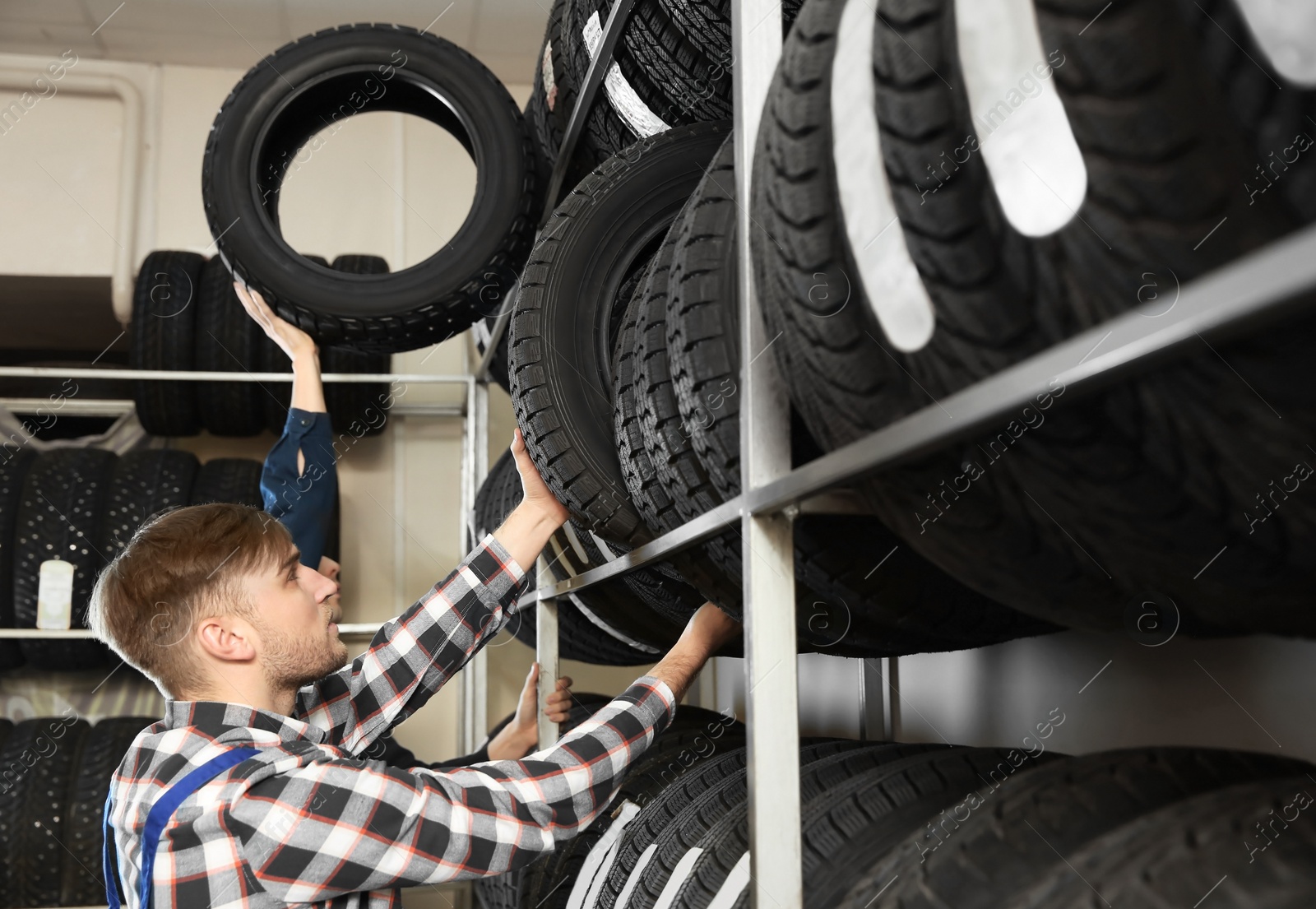 Photo of Young male mechanics with car tires in automobile service center