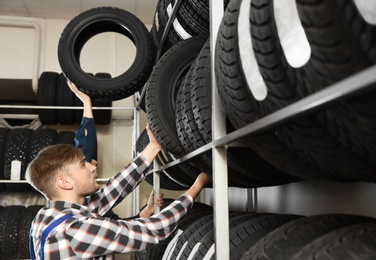 Young male mechanics with car tires in automobile service center