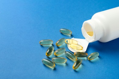 Photo of Bottle of vitamin capsules on blue background, closeup. Space for text