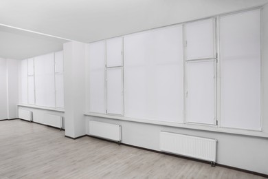 Photo of Windows covered with white roller blinds indoors