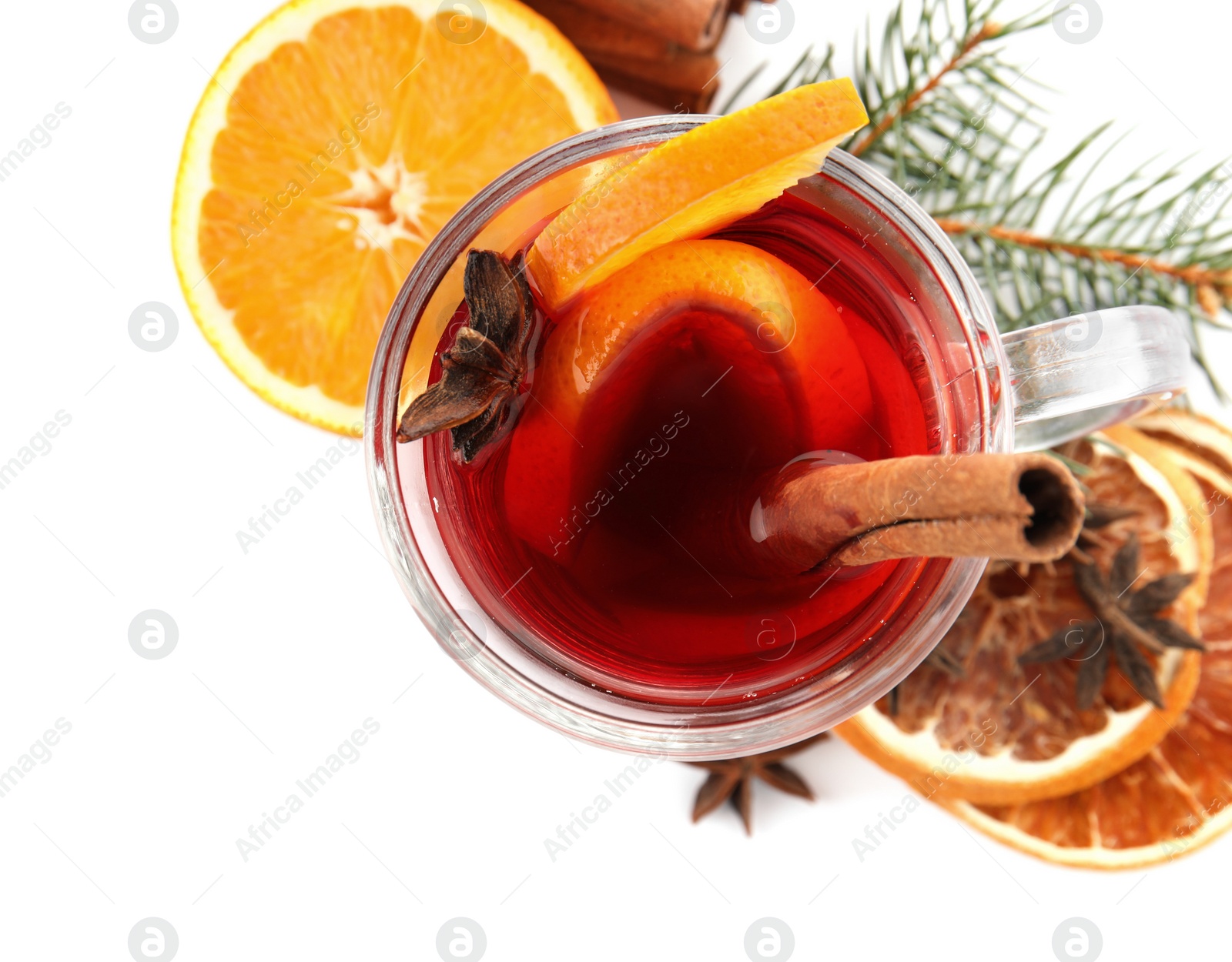 Photo of Glass cup of mulled wine, cinnamon, orange and fir branch on white background, top view