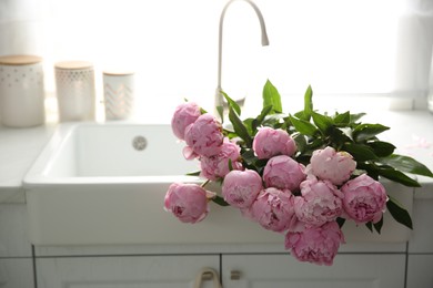 Photo of Bouquet of beautiful pink peonies in kitchen sink