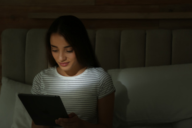 Photo of Happy woman using tablet in dark bedroom