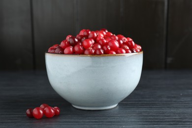 Photo of Cranberries in bowl on black wooden table, closeup