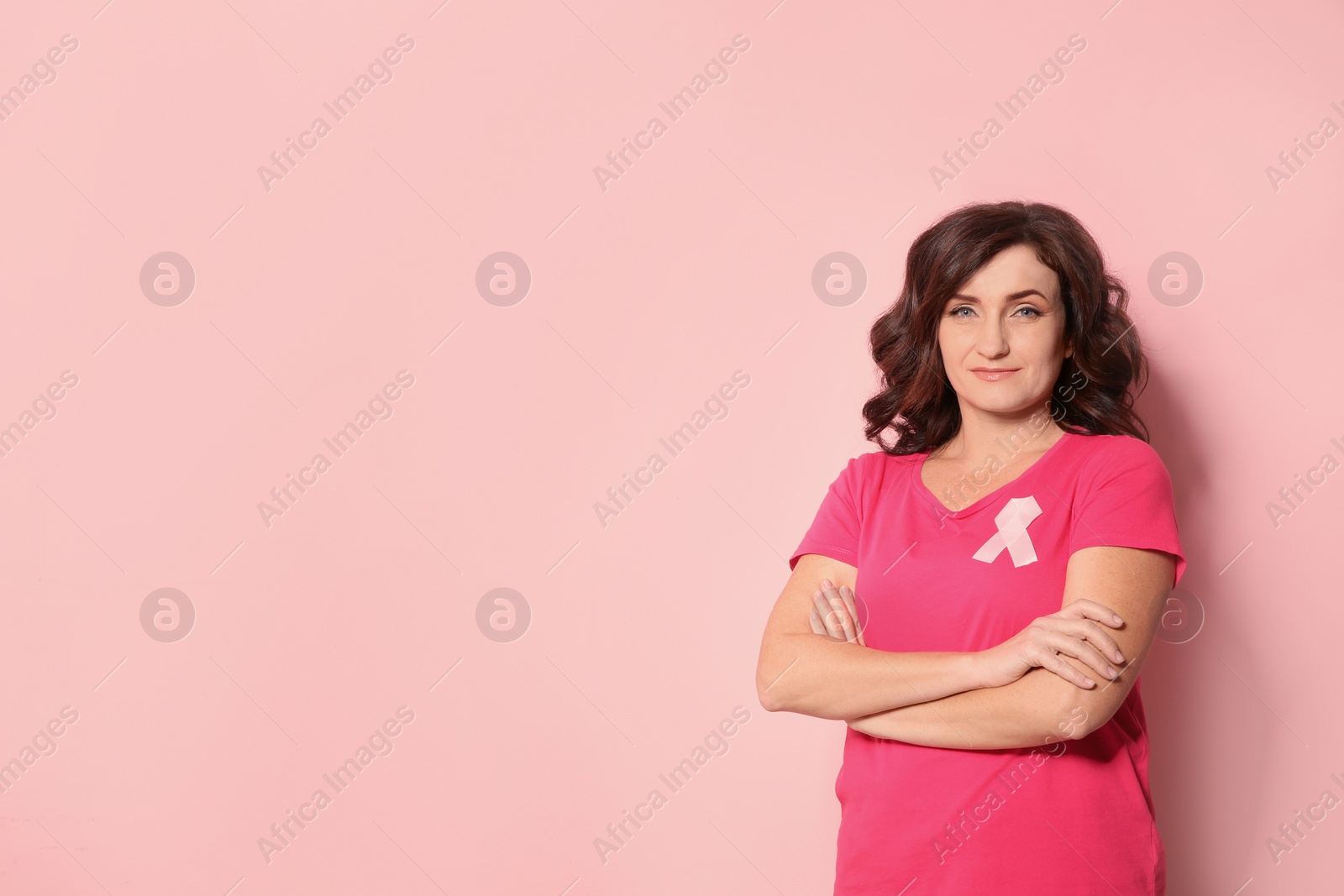 Photo of Woman with silk ribbon and space for text on color background. Breast cancer awareness concept