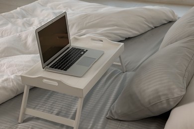Photo of White tray table with laptop on bed