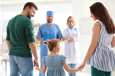 Photo of Little girl with parents visiting children's doctors in hospital