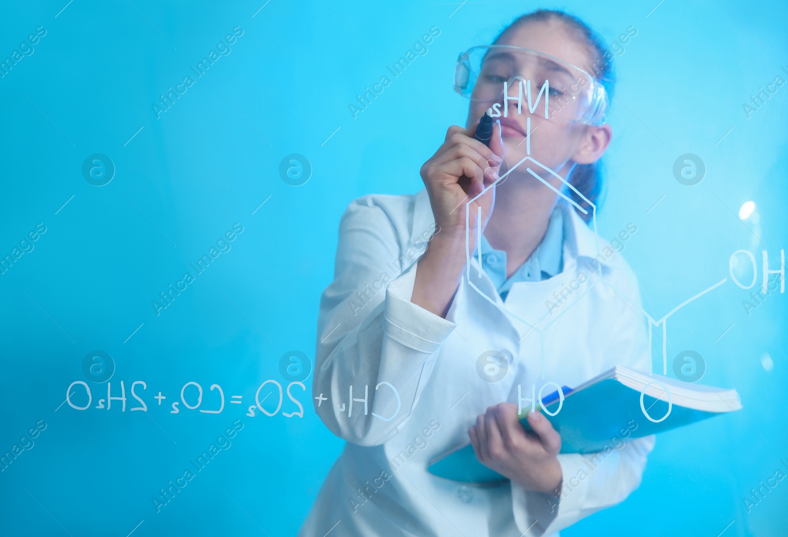 Photo of Schoolgirl writing chemistry formula on glass board against color background. Space for text