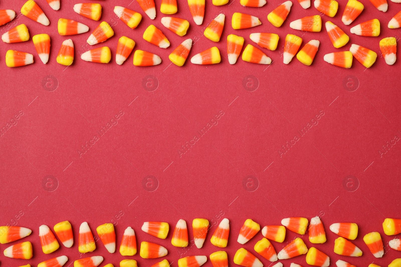 Photo of Flat lay composition with delicious candy corns and space for text on color background