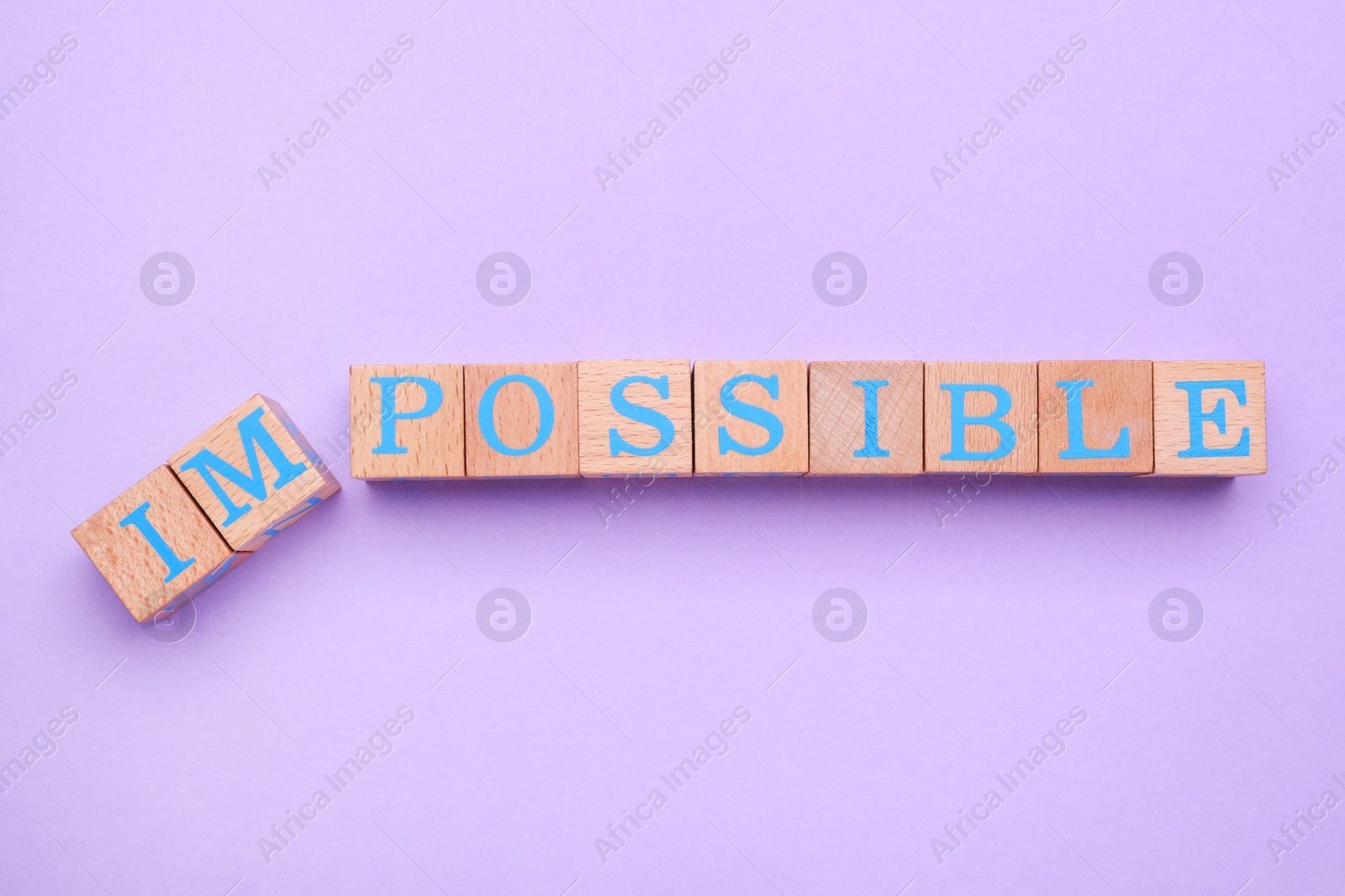 Photo of Motivation concept. Changing word from Impossible into Possible by removing wooden cubes on violet background, flat lay