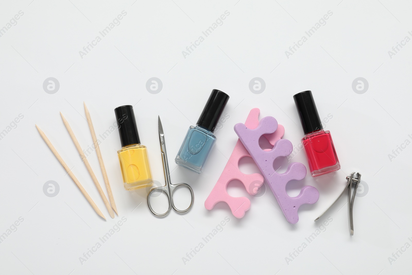 Photo of Nail polishes and set of pedicure tools on white background, flat lay