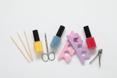 Photo of Nail polishes and set of pedicure tools on white background, flat lay